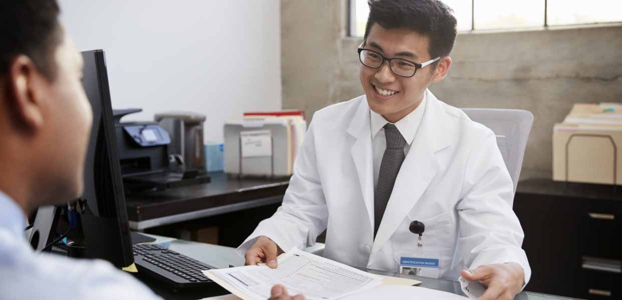 a man in a white lab coat sitting at a desk.