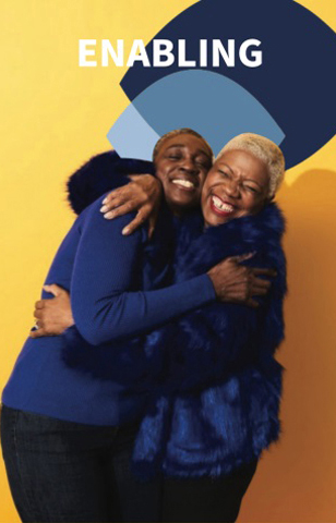 Two smiling people hugging joyfully under the word ENABLING